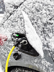 Obraz premium Ein mit Schnee bedecktes Auto wird an einer Ladesäule geladen, Düsseldorf, Deutschland