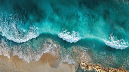 Aerial wave crashing against golden beach, green and white foam. 