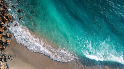 Aerial wave crashing against golden beach, green and white foam. 