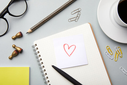 Office desk with stationery and a heart note symbolizing love