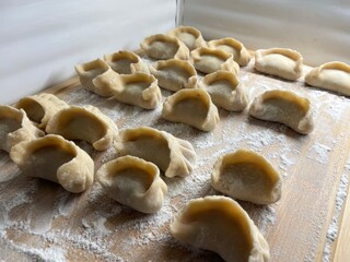 Homemade Handmade Dumplings on Wooden Cutting Board – Flour-Sprinkled Rustic Scene for Healthy Cooking & Preserves