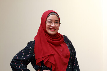 An Asian Muslim lady standing with one hand on her waist and smiling. Confidence expression.