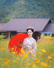 Traditional Japanese Woman in Furisode Kimono with red wagasa umbrella, fan, in a peaceful natural...