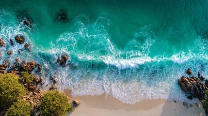 Aerial wave crashing against golden beach, green and white foam. 