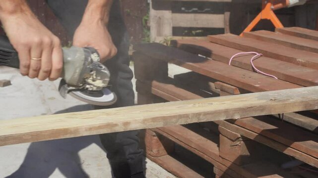 A worker grinds wood with a grinder