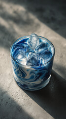 a glass of iced blue latte, marble-like swirl of blue and white milk