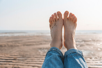 Relaxing by the beach with bare feet in the sand on a sunny day, enjoying the calm atmosphere and gentle ocean breeze