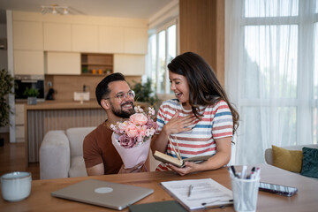Happy man giving flowers to surprised woman at home