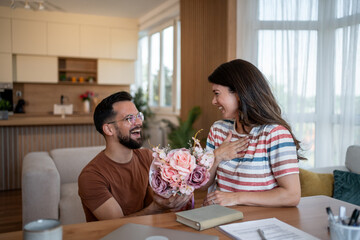 Happy man giving flowers to woman at home