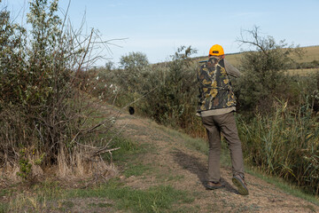 Hunter aiming with rifle while standing against sky