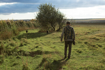 Mature man hunter with gun while walking on field.