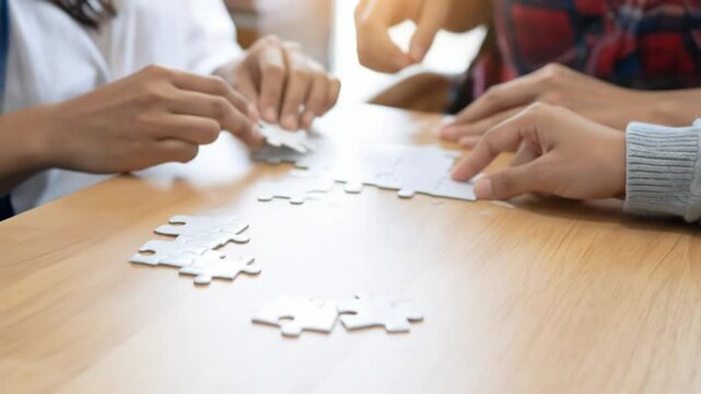 Close-up of diverse hands assembling a jigsaw puzzle on a light-wood table