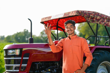 indian farmer standing with tractor at field