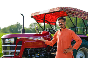 indian farmer standing with tractor at field