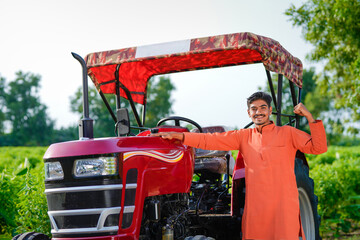 indian farmer standing with tractor at field