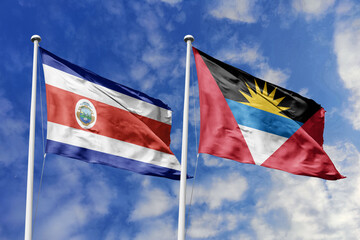 3D illustration. Costa Rica and Antigua and Barbuda flags waving in the sky. High detailed waving flag. 3D render. Flags fluttered in the cloudy sky, symbolizing diplomatic relations.