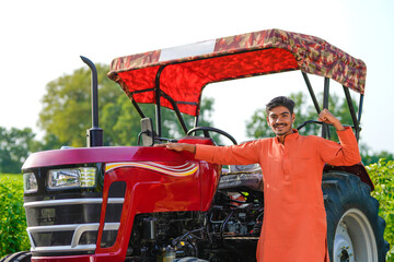 indian farmer standing with tractor at field