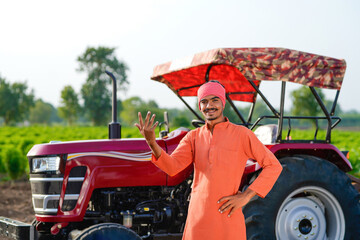 indian farmer standing with tractor at field