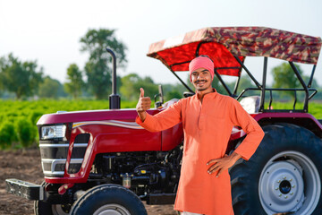 indian farmer standing with tractor at field