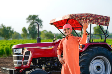 indian farmer standing with tractor at field