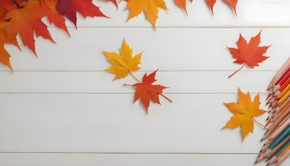 Colorful autumn leaves and pencils arranged on a white wooden surface.