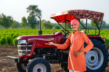 indian farmer standing with tractor at field