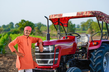 indian farmer standing with tractor at field