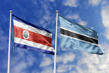 3D illustration. Costa Rica and Botswana flags waving in the sky. High detailed waving flag. 3D render. Flags fluttered in the cloudy sky, symbolizing diplomatic relations.