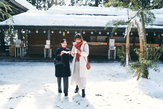 神社でおみくじを見せ合う日本人女性