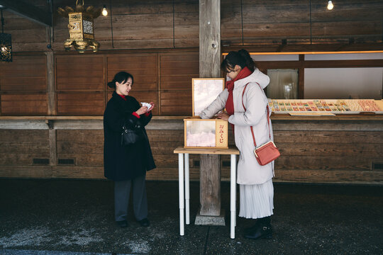 神社でおみくじを引く日本人女性