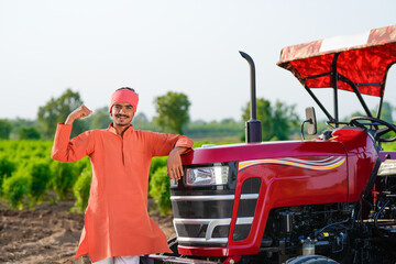 indian farmer standing with tractor at field