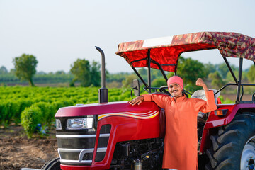 indian farmer standing with tractor at field