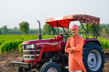indian farmer standing with tractor at field