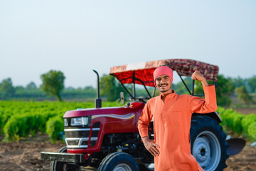 indian farmer standing with tractor at field