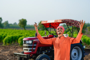 indian farmer standing with tractor at field