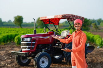 indian farmer standing with tractor at field