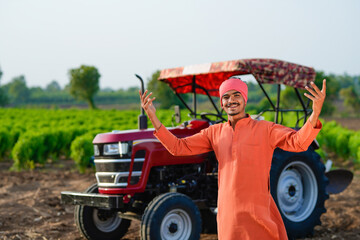 indian farmer standing with tractor at field