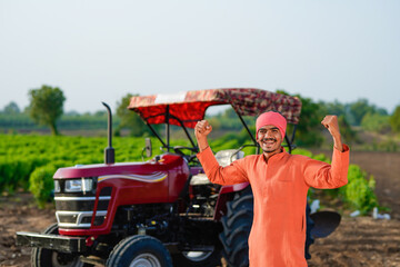 indian farmer standing with tractor at field