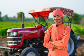 indian farmer standing with tractor at field