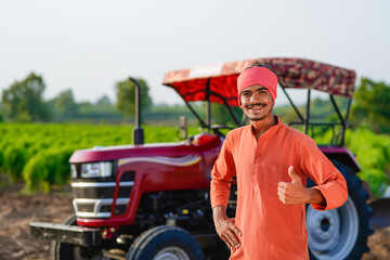 indian farmer standing with tractor at field