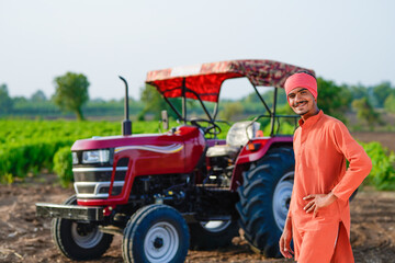 indian farmer standing with tractor at field