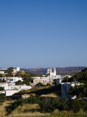 Fototapeta premium Cycladic hilltop village Plaka glowing in afternoon light with blue sky above.