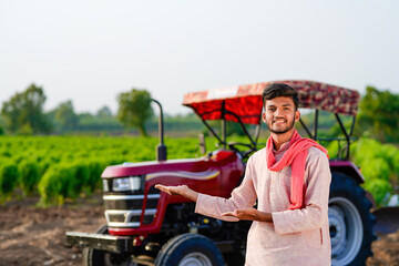 indian farmer standing with tractor at field