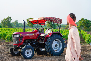 indian farmer standing with tractor at field
