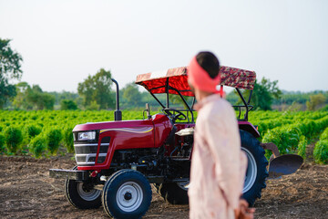 indian farmer standing with tractor at field