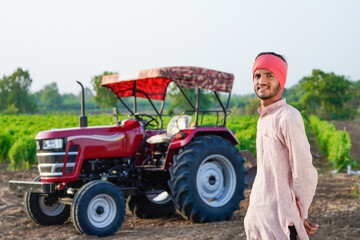 indian farmer standing with tractor at field