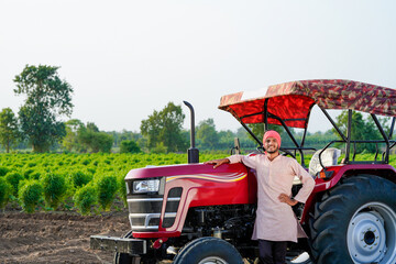 indian farmer standing with tractor at field
