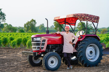 indian farmer standing with tractor at field