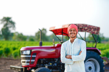 indian farmer standing with tractor at field