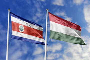 3D illustration. Costa Rica and Hungary flags waving in the sky. High detailed waving flag. 3D render. Flags fluttered in the cloudy sky, symbolizing diplomatic relations.